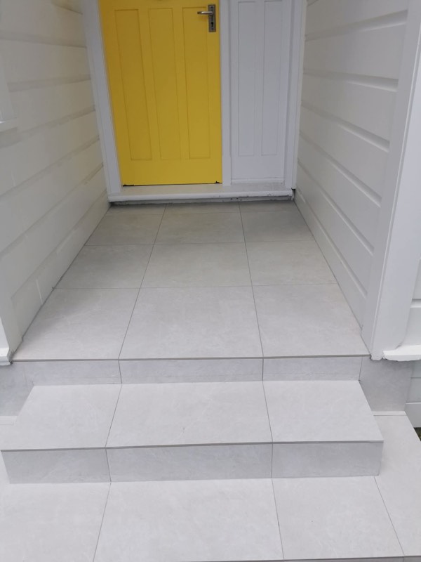 Tiled outdoor entry and steps leading to a bright yellow door