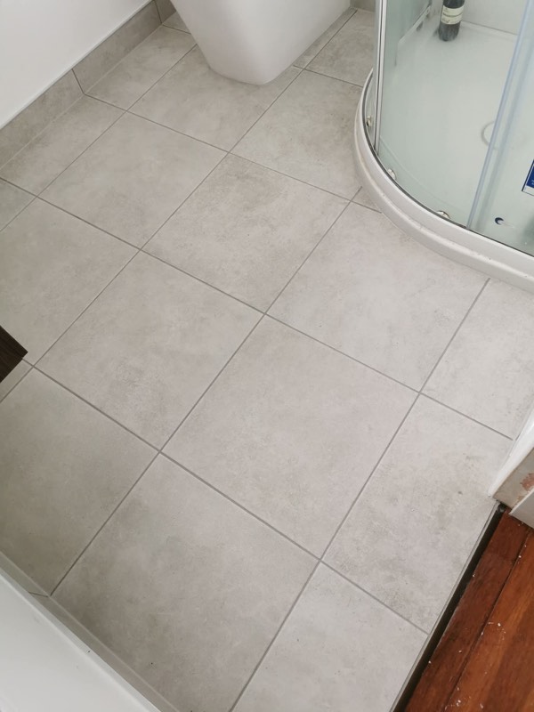 Light grey tiled bathroom floor with a rounded shower enclosure